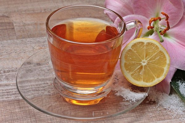 Grüner Tee mit Zitrusfrüchten: Glas mit Tee und einer Zitrone.