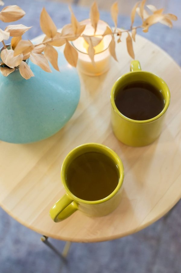 Kaffee oder Tee: Zwei Tassen mit Kaffee und grünem Tee bzw. Matcha Tee.