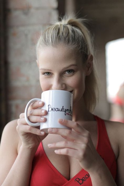 Tee Influencer / Tee Influencerin: Frau die Fitness Tee aus einer Tasse trinkt.