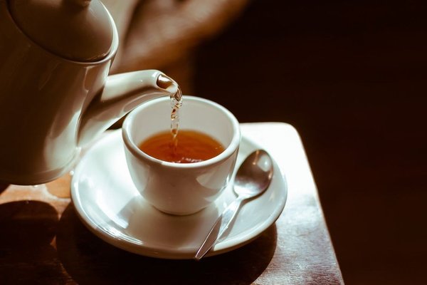 Eine Tasse die mit gesundem Tee eingegossen wird.